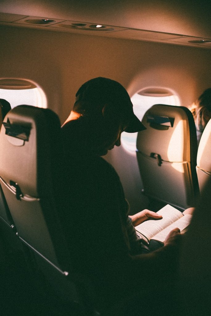 man sitting inside plane reading book